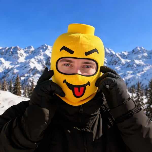 Person pulling the yellow mask on over their head, eyes visible, standing in snow