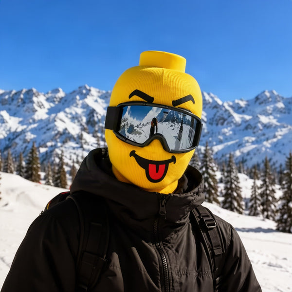 Skier on a snowy mountain wearing the yellow smiley mask with ski goggles